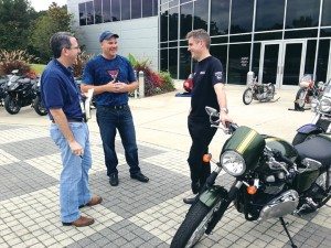 In a meeting of CEOs, a reporter visits with Greg Heichelbech (Triumph North America), middle, and Nick Bloor (Triumph Motorcycles Ltd) during the dealer meeting at Barber Motorsports Park in Birmingham, Ala.