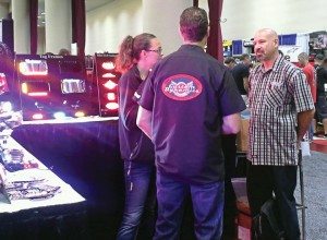 Megan Barrett, business manager of Custom Dynamics, and a colleague talk to a Parts Unlimited/Drag Specialties rep at the distributor’s 2013 National Vendor Presentation in Madison, Wis.